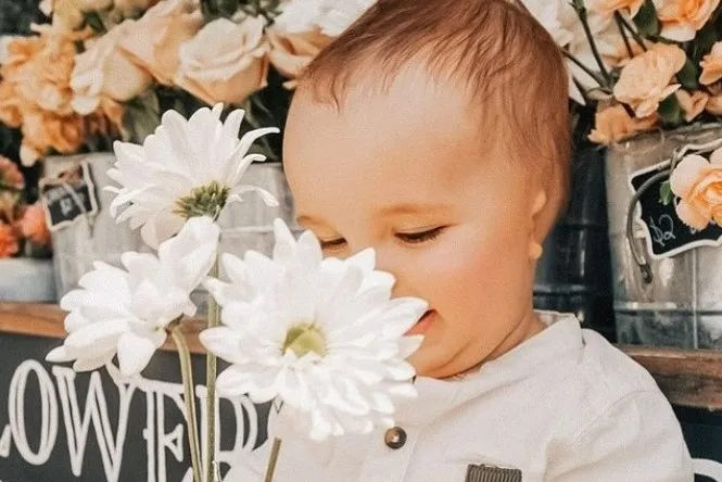 Baby with microtia smelling large white flowers