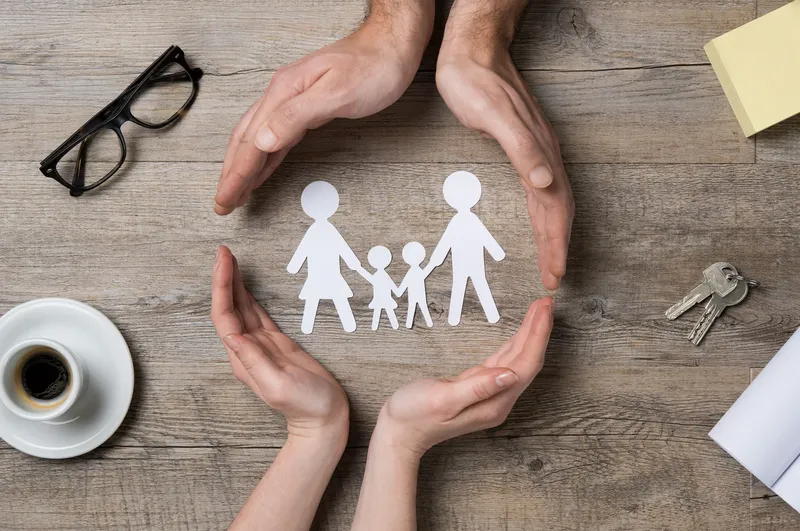 Image depicting community with hands around a paper cut-out family