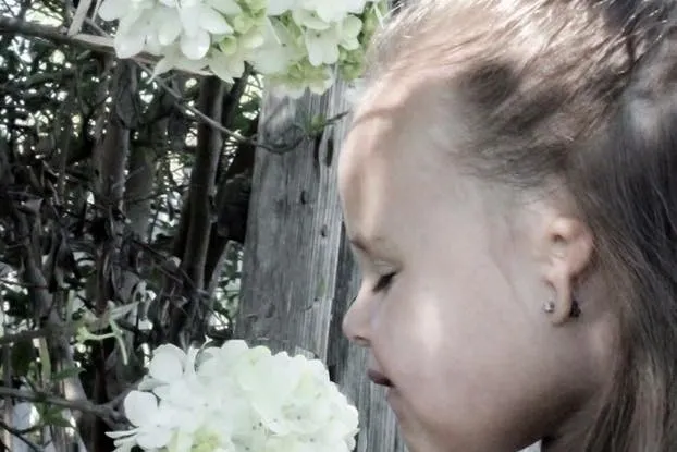 Young girl with microtia smelling a flower