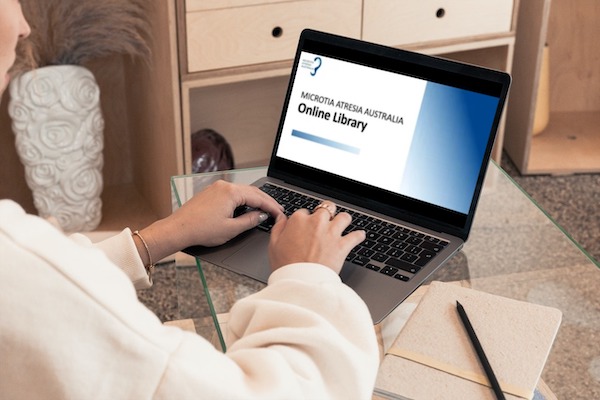 Woman viewing Microtia Atresia Australia Online Library on a laptop